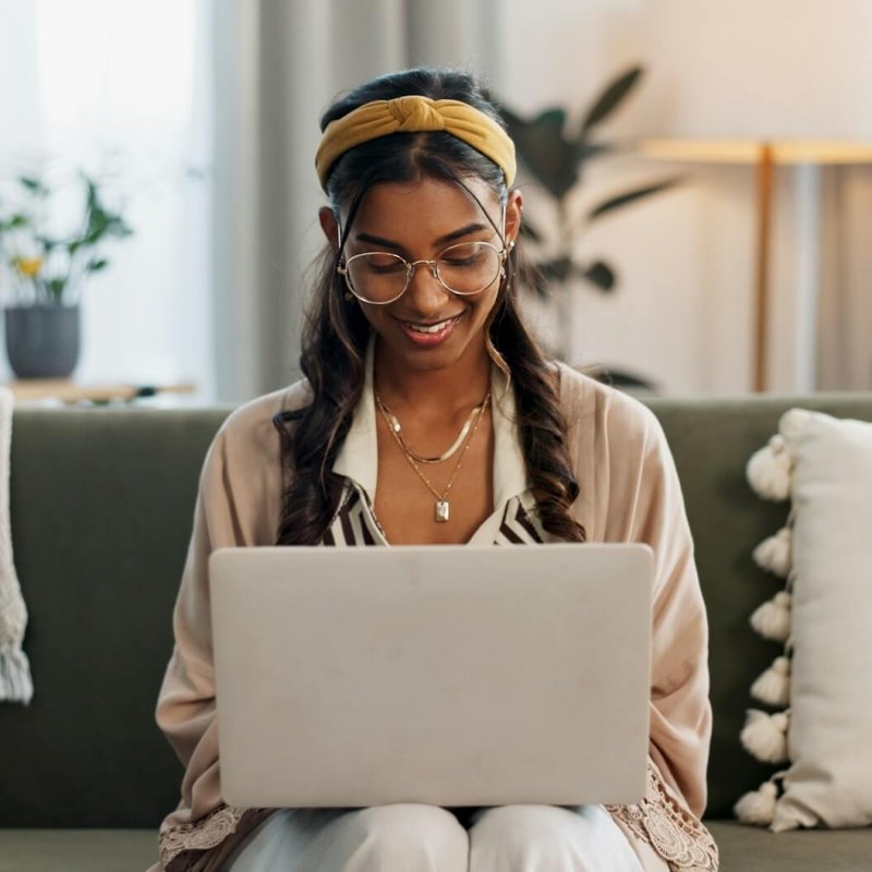 laptop-remote-work-and-happy-woman-on-a-sofa-for-social-media-research-or-reading-a-home-tech-f